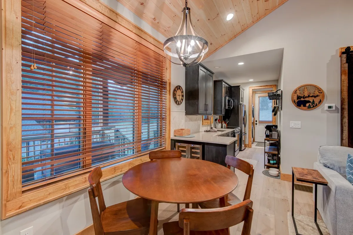 A warm and inviting open-plan dining and kitchen area, with a large table for family meals and windows bringing in natural light. The space flows effortlessly, showing how rooms are interconnected.