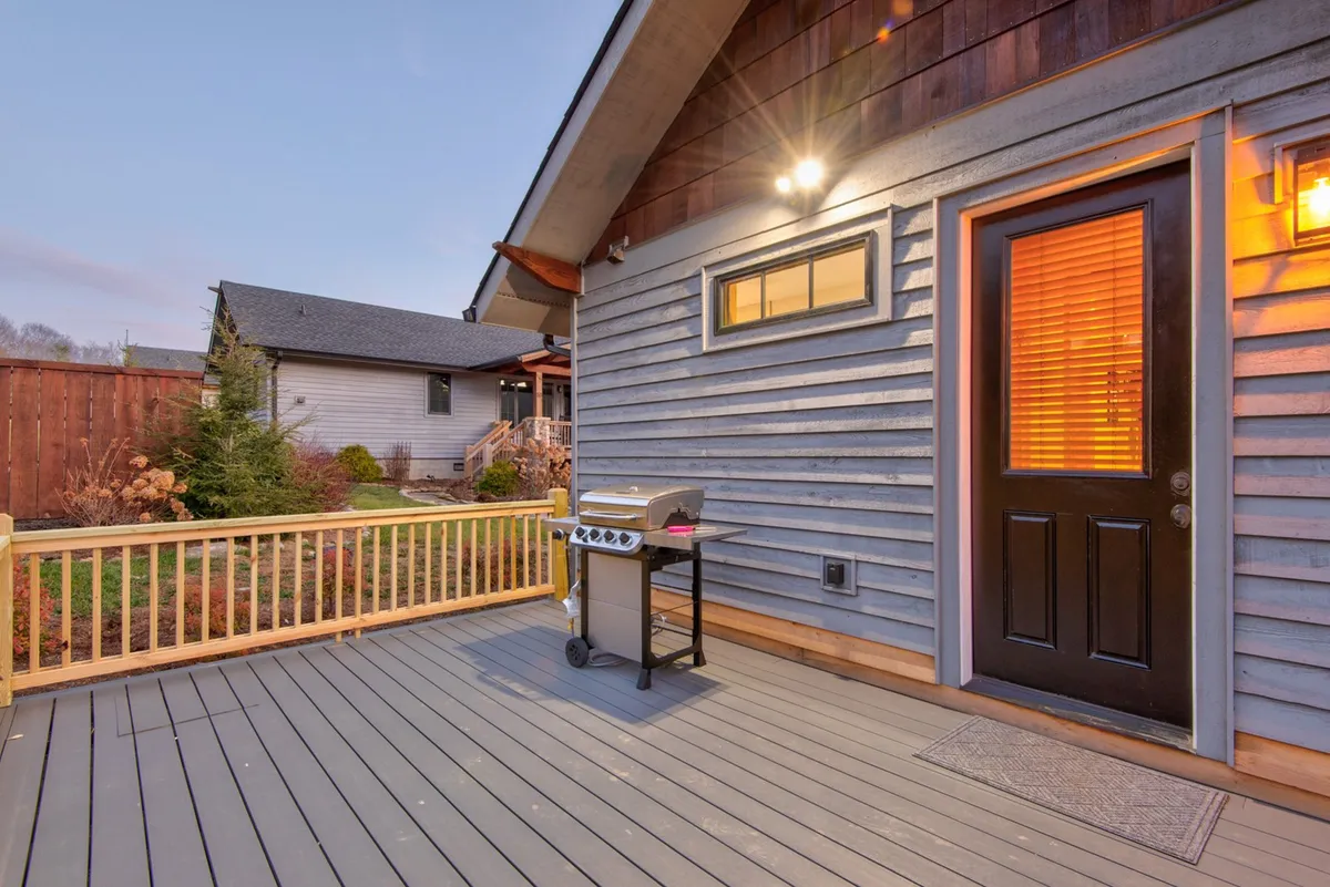 This image captures the exterior deck area of the home during sunset, featuring a grill and comfortable seating perfect for relaxing or entertaining after a day outdoors. The warm light and open setting invite you to enjoy the fresh mountain air and scenic views.