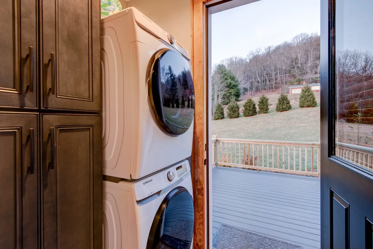 A dedicated laundry area featuring a modern washer and dryer, with a doorway offering easy access outside. The space is well-lit and functional, emphasizing convenience for daily chores.